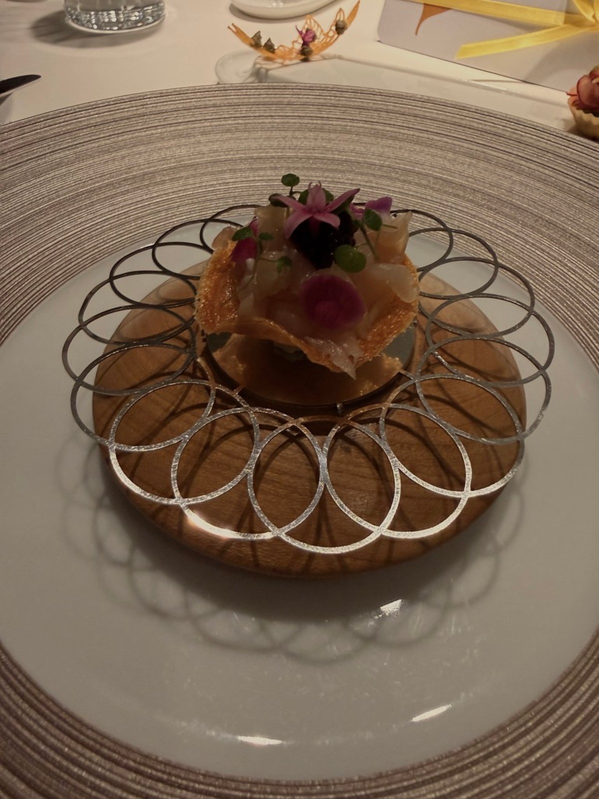 A raw-fish tartlet in a dark restaurant, as shot on a phone